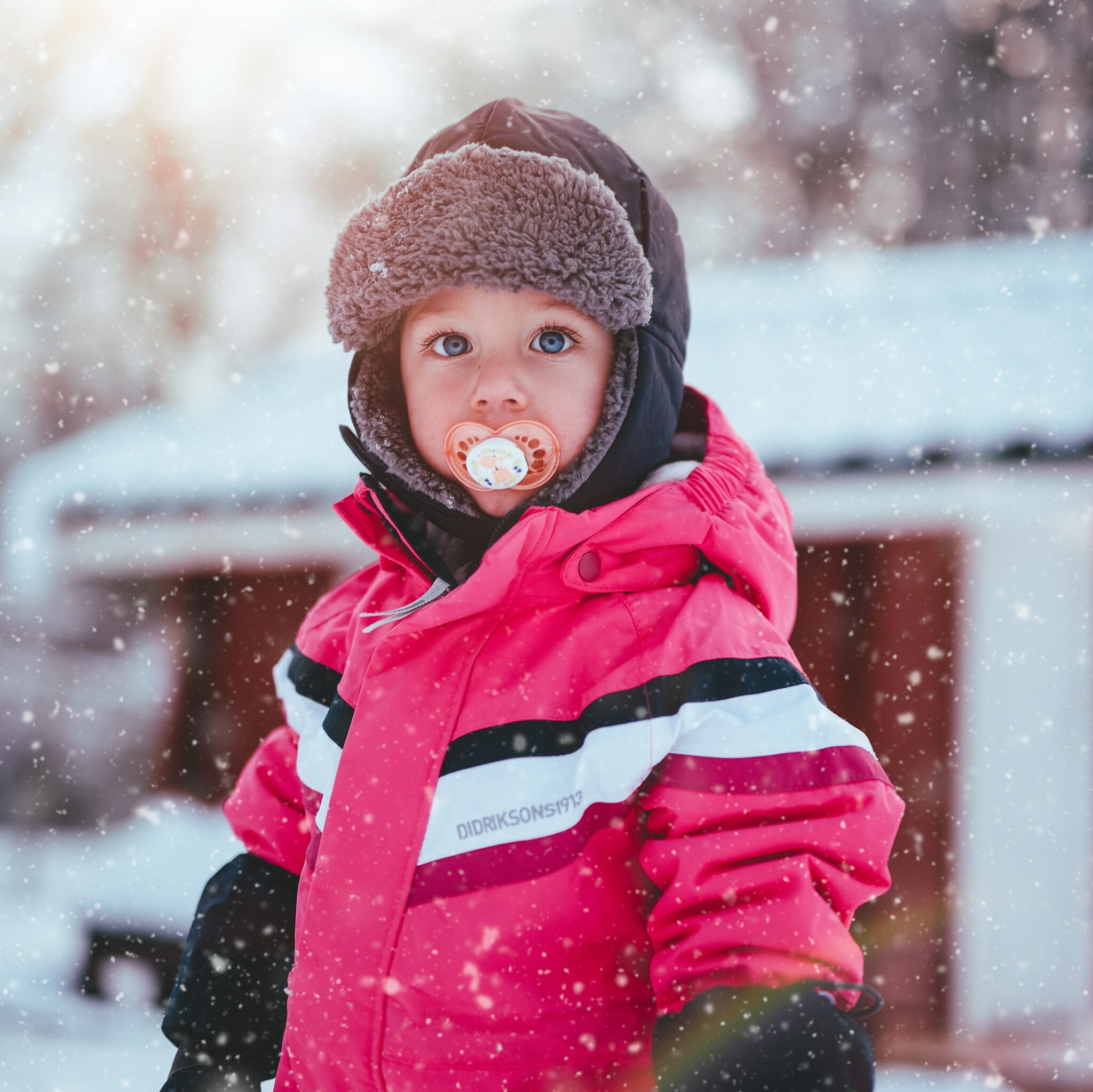 Enfant avec une tétine sous la neige